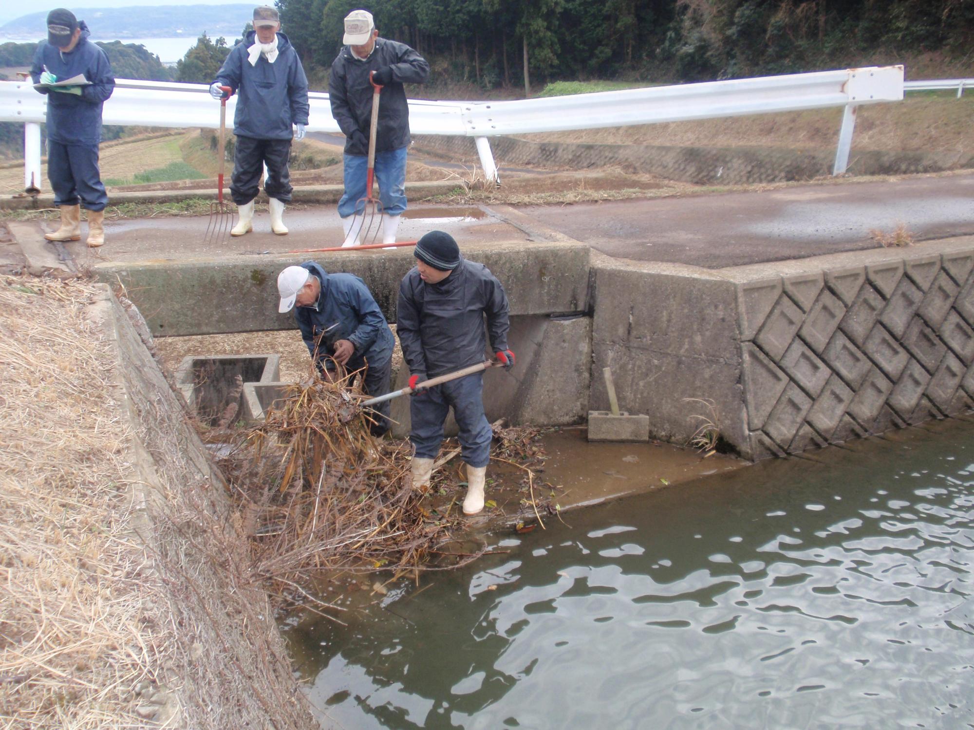 余水吐の除塵作業をする人々の写真