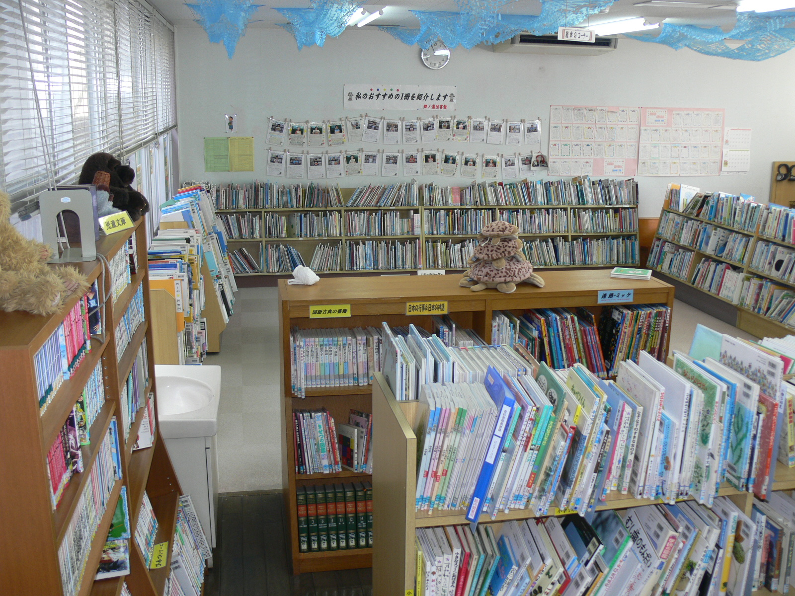 壁と窓に沿って3段ほどの本棚が置いてある1階図書館内の写真