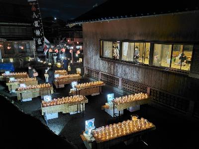 八坂神社（郷ノ浦）建物横に間隔をあけて並べられた長机の上に沢山のLEDキャンドルが淡い光を放っている写真